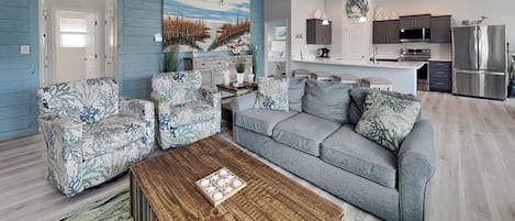 A living room with a sofa, two armchairs, a coffee table, and a painting on the wall.