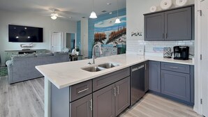 A modern kitchen with grey cabinets, a white countertop, and a built-in dishwasher. - Pelican's Landing (Rockport)