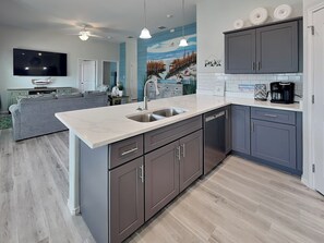 A modern kitchen with grey cabinets, a white countertop, and a built-in dishwasher. - Pelican's Landing (Rockport)
