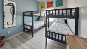 A room with bunk beds, a seahorse artwork, and colorful wall art. - Pelican's Landing (Rockport)