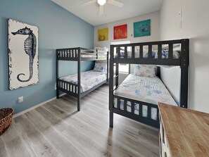 A room with bunk beds, a seahorse artwork, and colorful wall art. - Pelican's Landing (Rockport)