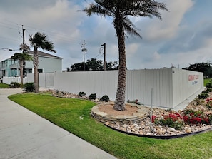 A residential area with a white fence, a palm tree, and a well-maintained lawn. - Pelican's Landing (Rockport)