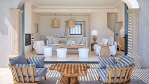 Amplia sala de estar con un sofá, dos sillones, una mesita de centro y una lámpara.