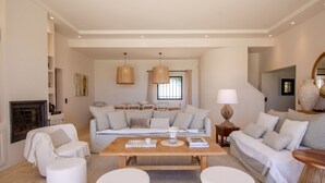 Un salón espacioso con un conjunto de sofás, una mesa de centro y una chimenea.