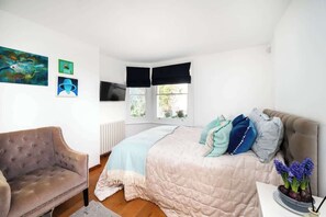 Ein Schlafzimmer mit einem Bett, einem Sessel, einem Fernseher und Bildern an der Wand.