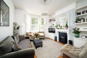Ein Wohnzimmer mit einer Couch, Sesseln, einem Couchtisch und einem Kamin.