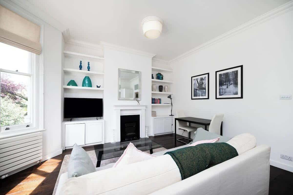 Un salon moderne avec un canapé blanc, une cheminée, un téléviseur à écran plat et un coin repas.
