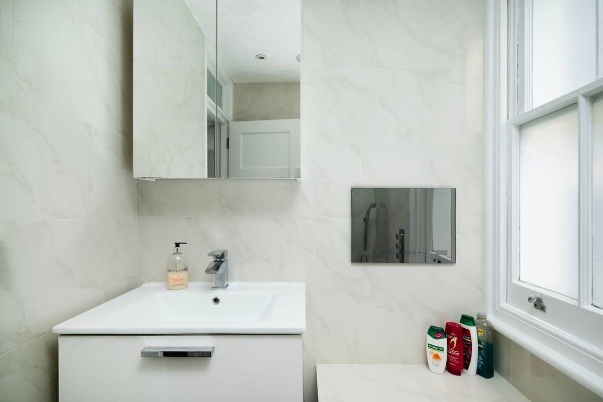A bathroom with a white sink, a mirror, and toiletries on the counter.