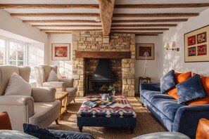 A living room with a stone fireplace, sofas, and a large window. - 4-Bed Cotswolds Getaway     Perfect for Families (Kingham)
