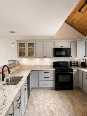 A kitchen with white cabinets, a black stove, a microwave, and a coffee maker.