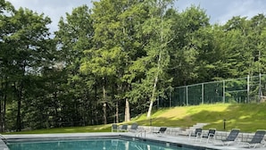 A swimming pool with a metal ladder, surrounded by a grassy area and trees. - Okemo Trailside: 3BR + Bonus Room, Hot Tub, Sauna & On-Demand Shuttle to Sachem (Ludlow)