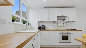 Een moderne keuken met witte kastjes, een houten aanrecht, een spoelbak en een oven.