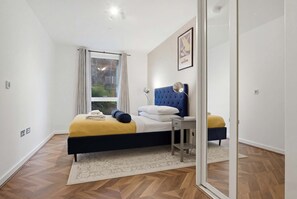 Ein Schlafzimmer mit Bett, Nachttisch und einem Fenster mit Vorhängen.