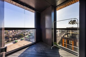 Ein Balkon mit Blick auf die Stadt, einem Wäscheständer und einer kleinen Pflanze.