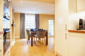 Une cuisine moderne avec un coin repas, un plancher en bois et une vue par la fenêtre.