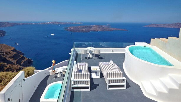 Une terrasse sur le toit avec une piscine, des chaises longues et une table sur laquelle se trouve un verre.
