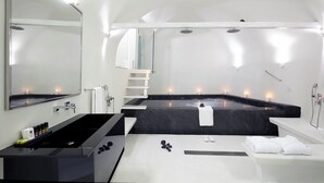 Une salle de bain moderne avec un grand miroir, une baignoire noire, un lavabo blanc et un espace douche.
