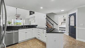 A modern kitchen with white cabinets, a black countertop, and a stainless steel dishwasher. - Luxury Lake & Golf Escape: 4BR & 4BTH Home + Gym,Near UIUC / U of I - Sleeps 11+ (Champaign)