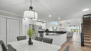 A modern kitchen with white cabinets, a marble dining table, and a central island. - Luxury Lake & Golf Escape: 4BR & 4BTH Home + Gym,Near UIUC / U of I - Sleeps 11+ (Champaign)