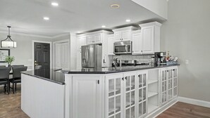 A modern kitchen with white cabinetry, a stainless steel refrigerator, a microwave, and a coffee station. - Luxury Lake & Golf Escape: 4BR & 4BTH Home + Gym,Near UIUC / U of I - Sleeps 11+ (Champaign)