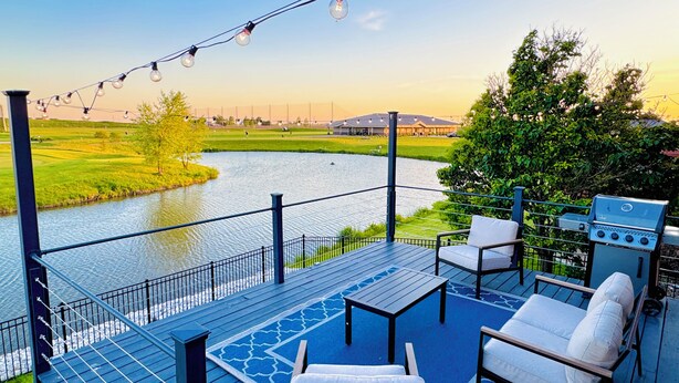 A deck with outdoor seating, a grill, and a view of a river and greenery. - Luxury Lake & Golf Escape: 4BR & 4BTH Home + Gym,Near UIUC / U of I - Sleeps 11+ (Champaign)