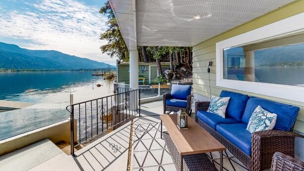 Een balkon met uitzicht op een meer, een blauwe bank en een houten tafel.