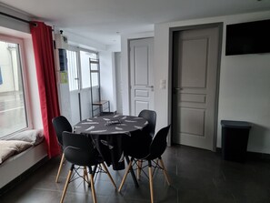 Un coin repas avec une table ronde, des chaises noires et un rideau rouge.