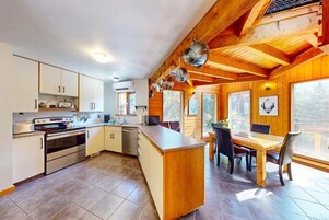 Uma cozinha com armários de madeira, um fogão e um espaço de jantar com mesa e cadeiras.
