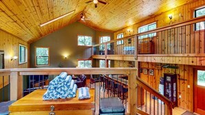 Interior de madeira em vários níveis, com área de jantar, bar e assentos.