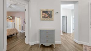 Une pièce comprenant un lit, une commode, un tableau encadré et un ventilateur de plafond.