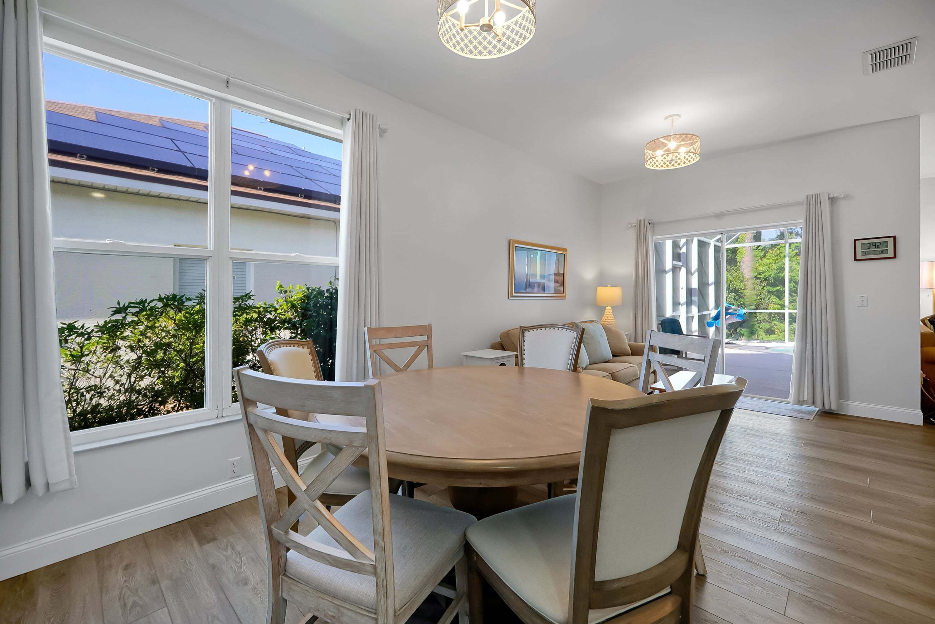 A dining area with a round table and chairs, large windows, and a view of the outdoors.