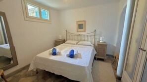 A bedroom with a bed, two bedside tables, a nightstand, a window, and a framed picture on the wall. - Panoramic Sea View Villa Near Beach and Town (Mykonos)