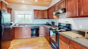 Una cocina con armarios de madera, un refrigerador de acero inoxidable, una estufa y una ventana.