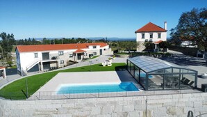 Una villa moderna con piscina, un área de estar techada al aire libre y vistas a las montañas.