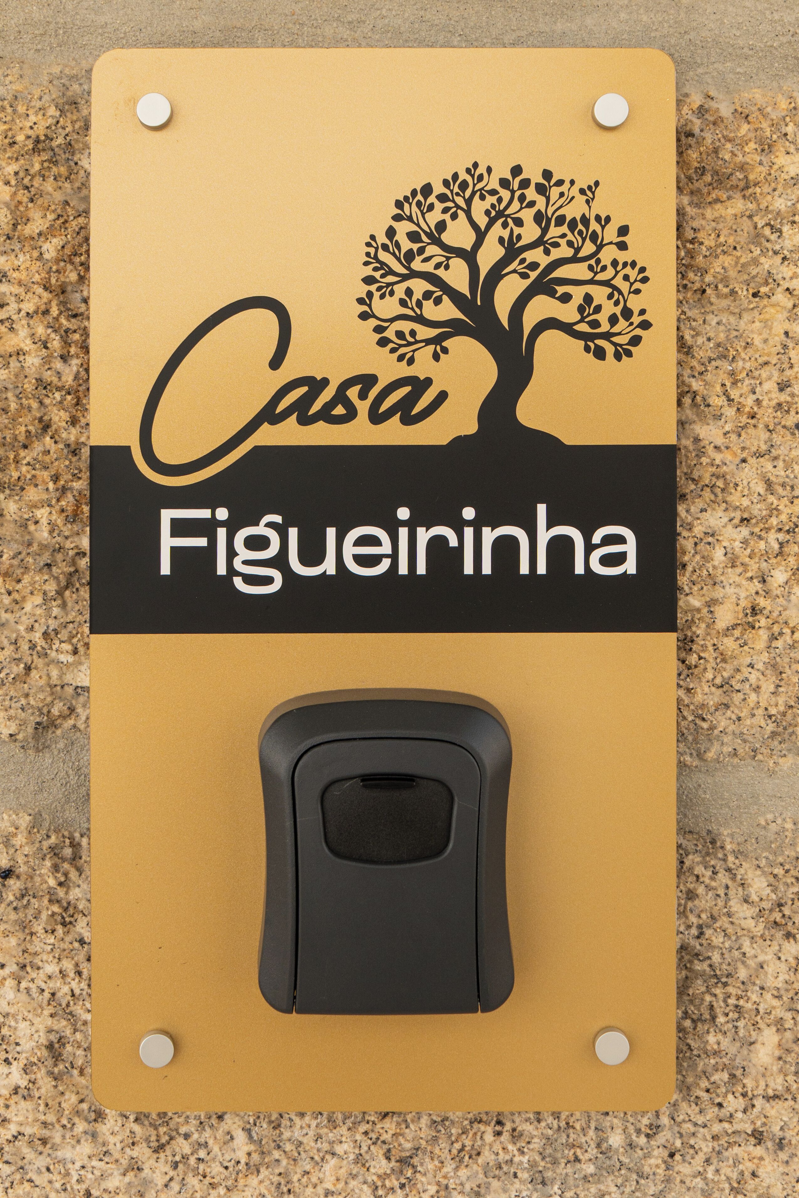 A sign with a tree silhouette and the text 'Casa Figueirinha' on a yellow background.
