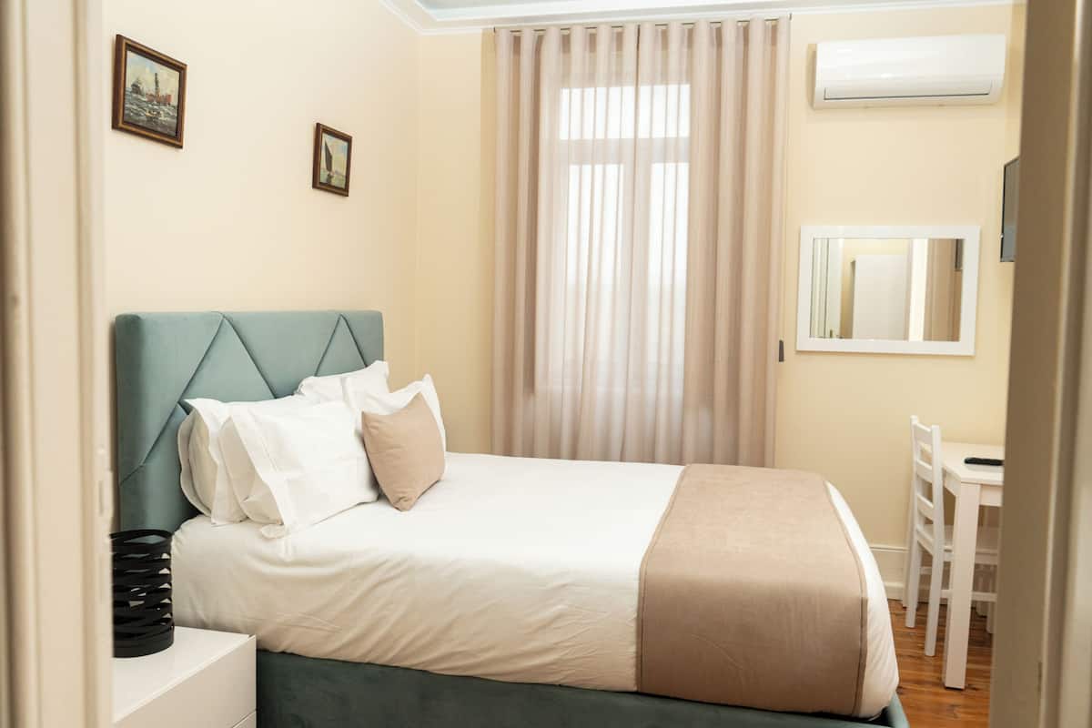 Une chambre bien rangée, avec un lit, une table de chevet et un bureau avec une chaise.