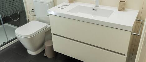 A bathroom with a toilet, sink, and shower.