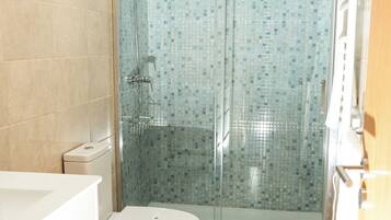 Un baño con ducha, inodoro y lavabo.