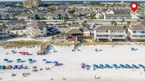 Een hotel aan het strand, met meerdere gebouwen, een zandstrand en parasols.