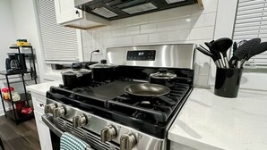 A kitchen with a stainless steel stove, a microwave above it, and a white tiled backsplash. - Modern Berwyn Retreat - 15 Min to Midway - Easy Access to Chicago (Berwyn)