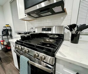 A kitchen with a stainless steel stove, a microwave above it, and a white tiled backsplash. - Modern Berwyn Retreat - 15 Min to Midway - Easy Access to Chicago (Berwyn)
