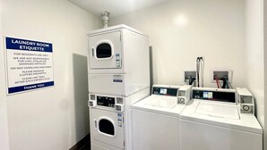 A laundry room with stacked washers and dryers, a sign with laundry etiquette, and a control panel on the dryers. - Modern Berwyn Retreat - 15 Min to Midway - Easy Access to Chicago (Berwyn)