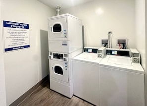 A laundry room with stacked washers and dryers, a sign with laundry etiquette, and a control panel on the dryers. - Modern Berwyn Retreat - 15 Min to Midway - Easy Access to Chicago (Berwyn)