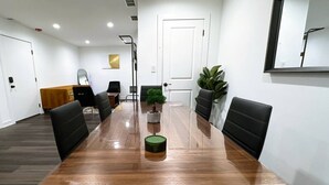 A conference room with a long wooden table, black chairs, a small potted plant, and a white door. - Modern Berwyn Retreat - 15 Min to Midway - Easy Access to Chicago (Berwyn)