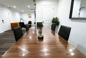 A conference room with a long wooden table, black chairs, a small potted plant, and a white door. - Modern Berwyn Retreat - 15 Min to Midway - Easy Access to Chicago (Berwyn)