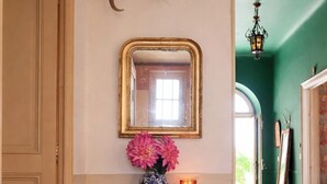 A hallway with a decorative console table, a mirror, a vase with flowers, and a candle. - Maison de maître en Provence - Charming and old-fashioned in the countryside (Beaucaire)