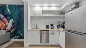 Een moderne keuken met witte kasten, roestvrijstalen apparatuur en een houten aanrecht.