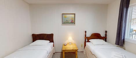 A small, clean room with two single beds, a nightstand with a lamp, and a picture on the wall.