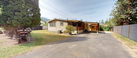 Une maison de campagne de plain-pied avec un porche à l’avant, un petit jardin et une allée pavée.