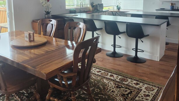 A modern kitchen with a wooden dining table, bar stools, and a large island.